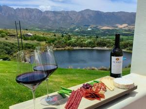 una copa de vino y un plato de comida y una botella de vino en The Oaks Tulbagh, en Tulbagh