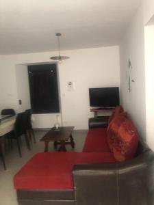 sala de estar con sofá rojo y mesa en Gîtes chez Sylvie, en Arreau
