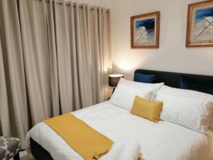 a bedroom with a white bed with a yellow blanket at The Blyde Lagoon, Pretoria in Pretoria +54 photos