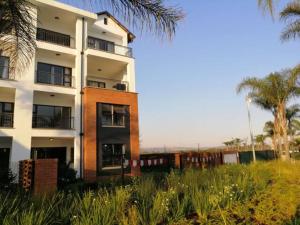 wysoki budynek z palmami przed nim w obiekcie The Blyde Lagoon, Pretoria w mieście Pretoria
