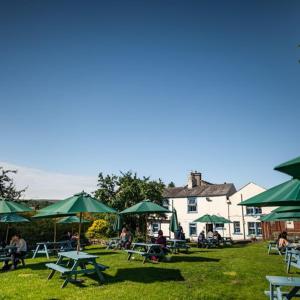 a group of picnic tables with green umbrellas at The Wheatsheaf Inn in Ingleton 