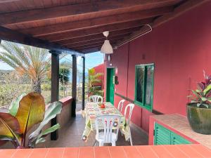 ein rotes Haus mit einem Tisch und Stühlen auf einer Terrasse in der Unterkunft Finca la Gaviota - Terazza in Icod de los Vinos