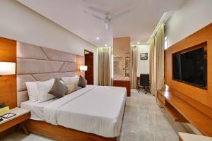 a bedroom with a large bed and a flat screen tv at The Fern Residency Ajmer in Ajmer