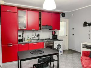 una cocina con armarios rojos y una mesa en una habitación en MYHOUSE INN FERMATA PARADISO - Affitti Brevi Italia, en Collegno