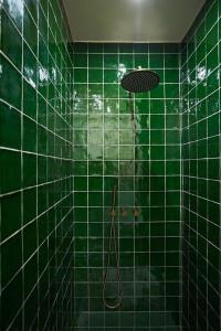 uma casa de banho com azulejos verdes e um chuveiro com azulejos verdes. em Διαμέρισμα σε διατηρητέο κτίριο em Chalkida