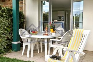 biały stół i krzesła na patio w obiekcie LocaLise - A06 - Entièrement de plain-pied avec petite vue mer - Donnant sur la piscine et le jardin - wifi inclus - draps inclus - w mieście Guilvinec