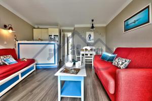 salon z czerwoną kanapą i stołem w obiekcie LocaLise - A06 - Entièrement de plain-pied avec petite vue mer - Donnant sur la piscine et le jardin - wifi inclus - draps inclus - w mieście Guilvinec