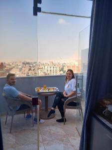 Ein Mann und eine Frau sitzen an einem Tisch im Fenster in der Unterkunft Pyramids Orion inn in Kairo