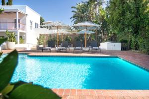 a swimming pool with chairs and umbrellas next to a house at Middedorp Manor in Stellenbosch