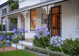 a white house with purple flowers in the front yard at Middedorp Manor in Stellenbosch