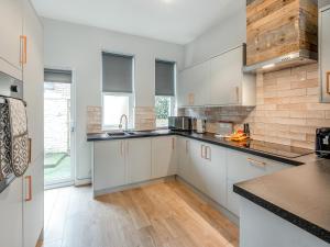 a kitchen with white cabinets and a wooden floor at Apartment One - Uk45352 in Southport