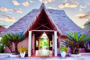 un bâtiment avec un toit pointu et des palmiers devant dans l'établissement Mandarin Resort Zanzibar, à Kizimkazi