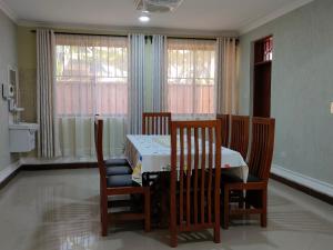 uma sala de jantar com mesa, cadeiras e janelas em Keeney House at St. Gabriel's em Arusha