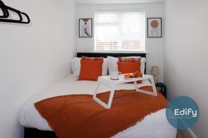 a bed with an orange blanket and a white table at Modernised House Close To City Centre in Southampton