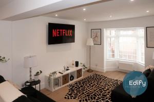 a living room with a couch and a tv on the wall at Modernised House Close To City Centre in Southampton