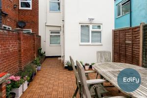 a patio with a wooden table and chairs at Modernised House Close To City Centre in Southampton