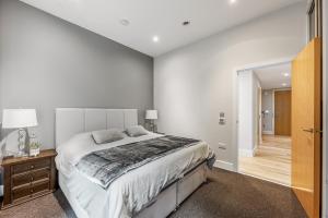 Un dormitorio blanco con una cama grande y un pasillo en Large Modern One Bedroom Apartment (nearly 800 ft), en Londres