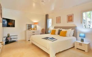um quarto com uma grande cama branca com almofadas laranja em Saint Barth Villa 1 em Saint-Jean