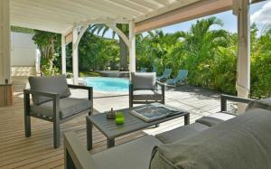 une terrasse avec un canapé et des chaises ainsi qu'une piscine dans l'établissement Saint Barth Villa 1, à Saint-Jean