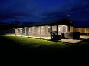 a small house with a lit up front of it at Ash Lodge - Exclusive Lodge with Hot Tub and stunning views in Bradpole