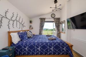 a bedroom with a blue bed and a window at Ash Lodge - Exclusive Lodge with Hot Tub and stunning views in Bradpole