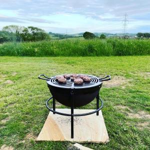 una griglia con sopra della carne in un campo di The Acorn - Luxury Shepherds Hut hot tub panoramic views a Bradpole