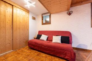 ein rotes Sofa in einem Zimmer mit Holzwänden in der Unterkunft L'Eglantine - Appt avec mezzanine à la montagne in Crest-Voland