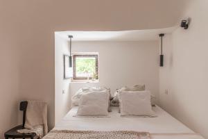 a bedroom with a bed with white sheets and a window at Trulli Piovanello in Castellana Grotte