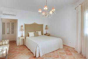 um quarto com uma cama branca e um lustre em Villa Costa Rica na Galé mais 21 fotografias