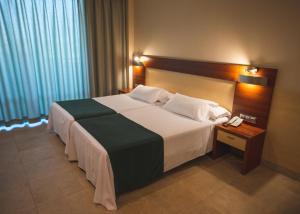 a large bed in a hotel room with a telephone at Hotel Deloix 4* Sup in Benidorm