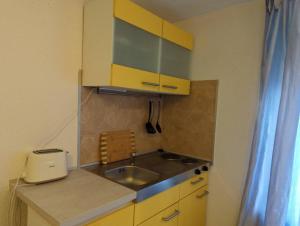 una pequeña cocina con fregadero y armarios amarillos en L8 Street Ladenburg Mannheim - Mitarbeiterwohnung zum Bestpreis finden, en Ladenburg