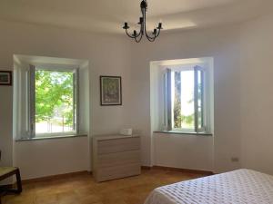 1 dormitorio con 1 cama, 2 ventanas y vestidor en Villa La Faggetina en Gambarie dʼAspromonte