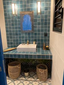 Baño de azulejos azules con lavabo y 2 cestas en Le Riad Private Pool, en Saint-Pierre