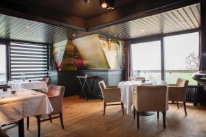 un comedor con mesas, sillas y ventanas en Grand Hotel Beatrix en Den Helder