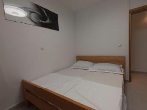 uma cama com lençóis brancos e uma foto na parede em Apartment Romana - next to the sea em Novalja