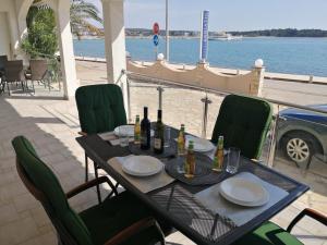 uma mesa com garrafas de vinho e pratos numa varanda em Apartment Romana - next to the sea em Novalja