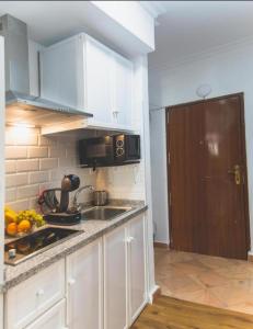 cocina con armarios blancos, fregadero y microondas en BaÑos - Casa Sevillana en Sevilla