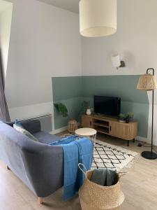 普雷讷夫昂德雷Studio proche de la mer à Pléneuf-Val-André的客厅里有一张蓝色沙发和一台电视
