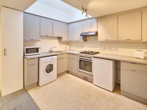 a kitchen with white cabinets and a washer and dryer at Host & Stay - Queen's Corner in Canterbury