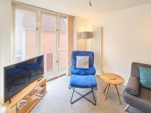 a living room with a blue chair and a television at Host & Stay - Queen's Corner in Canterbury