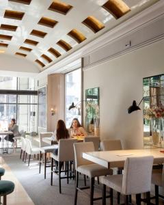 personas sentadas en mesas en un restaurante con techo artesonado en Hotel Santo Domingo, en Madrid