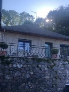 une maison avec un balcon au-dessus d'un mur en pierre dans l'établissement Maison individuelle a Arreau, à Arreau