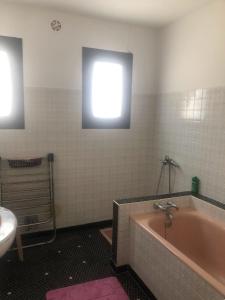 La salle de bains est pourvue d'une baignoire, d'un lavabo et d'une fenêtre. dans l'établissement Maison individuelle a Arreau, à Arreau