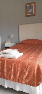a bedroom with a bed with an orange comforter at Hotel Crystal in Neuquén