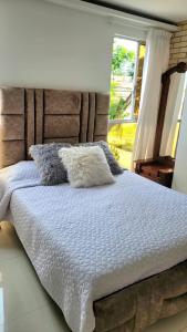 ein Bett mit zwei Kissen neben einem Fenster in der Unterkunft El samán in Cartago