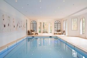 una piscina en una casa con paredes y ventanas blancas en Demeure d'Hôtes Haec Otia en Le Touquet-Paris-Plage