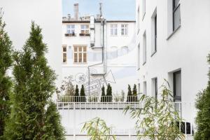 波兹南Aparthotel City Break Plac Wolności 6的白色的建筑,设有树木阳台