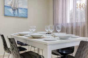 - une table blanche avec des bols et des verres à vin dans l'établissement Charming 2BR home w/access to pool in Marsaskala by 360 Estates, à Marsaskala