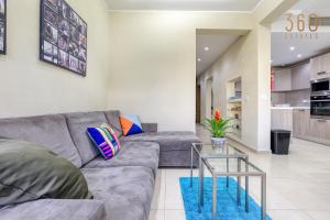 - un salon avec un canapé gris et une table en verre dans l'établissement Charming 2BR home w/access to pool in Marsaskala by 360 Estates, à Marsaskala
