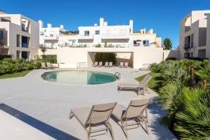 a patio with chairs and a swimming pool at Luxurious & Premium Flat - Pool & Gym in Tavira
